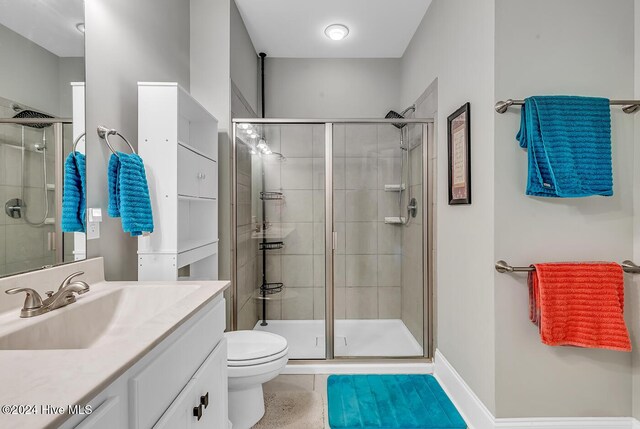 bathroom with toilet, vanity, tile patterned floors, and an enclosed shower