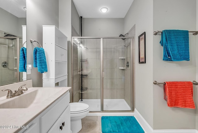 bathroom featuring toilet, a shower stall, vanity, and baseboards