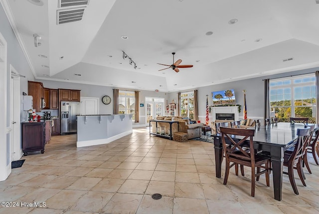 dining area with a raised ceiling, ceiling fan, ornamental molding, and light tile patterned flooring