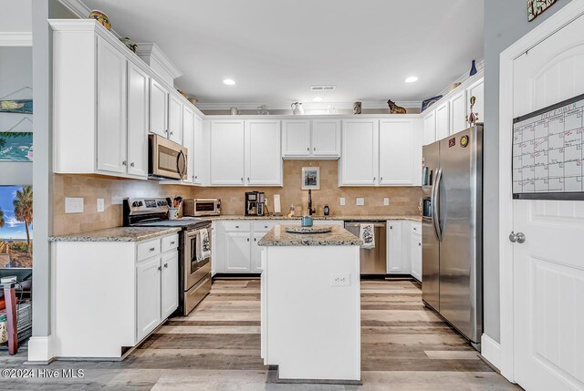 kitchen featuring ceiling fan with notable chandelier, a center island, stainless steel appliances, and white cabinetry