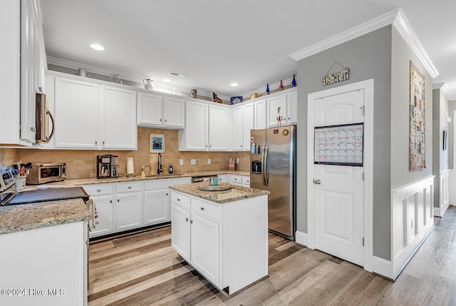 kitchen with white cabinets, appliances with stainless steel finishes, a center island, light stone countertops, and a sink