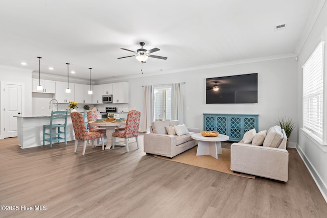 living room featuring crown molding, sink, ceiling fan, and light hardwood / wood-style flooring