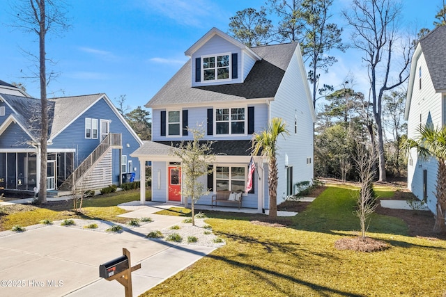 1163 N Caswell Ave, Southport, NC 28461 - view of front of property featuring a shingled roof, a front lawn, a sunroom, and a porch