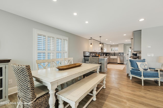 dining space featuring light wood finished floors, baseboards, and recessed lighting