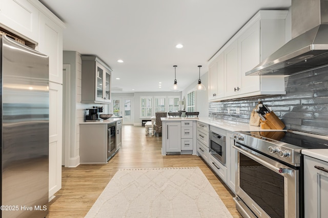 kitchen featuring wall chimney exhaust hood, appliances with stainless steel finishes, light countertops, and backsplash