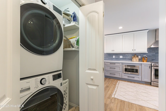 laundry area with light wood-style floors, stacked washer / dryer, laundry area, and recessed lighting