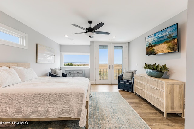 bedroom with access to outside, french doors, multiple windows, and wood finished floors