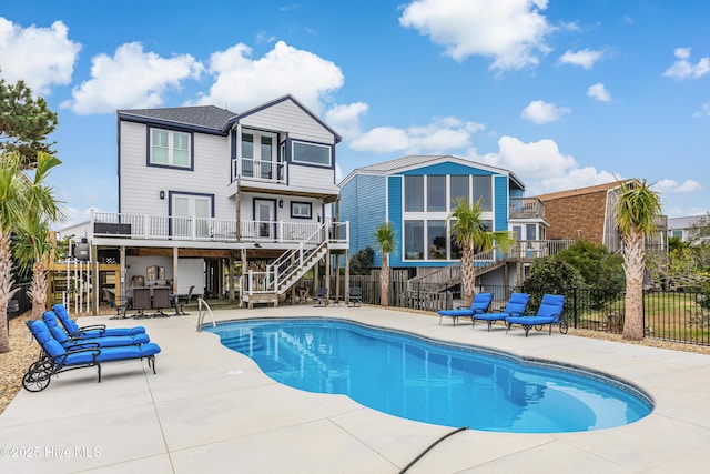 rear view of house with a fenced in pool, a patio, a balcony, stairway, and fence