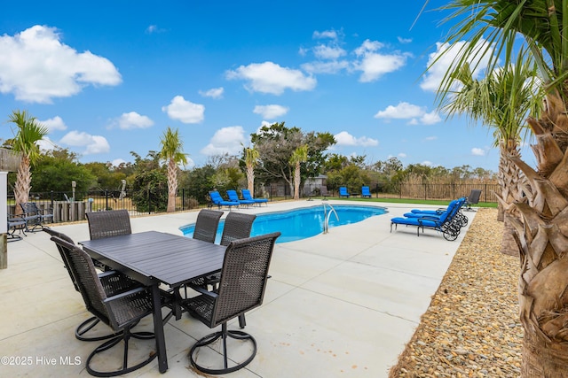 view of swimming pool featuring a patio, outdoor dining area, fence, and a fenced in pool