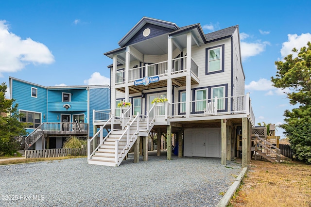 raised beach house featuring a garage, gravel driveway, a carport, and stairs