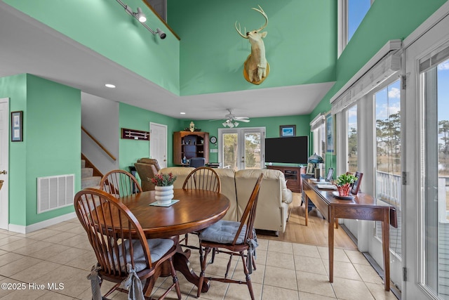 dining area with a towering ceiling, ceiling fan, french doors, and light tile patterned flooring