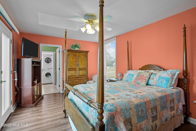 bedroom with multiple windows, ceiling fan, light hardwood / wood-style floors, and stacked washer / drying machine