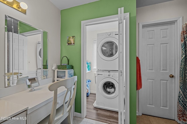 laundry area with stacked washer and dryer and light tile patterned flooring