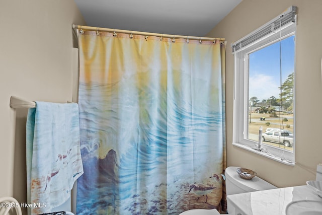 bathroom featuring a shower with curtain, vanity, toilet, and a wealth of natural light