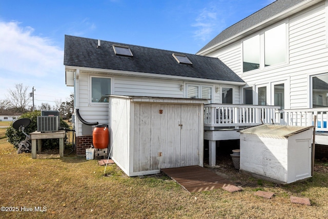 back of property featuring a lawn, a deck, and central AC