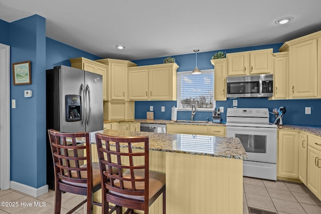 kitchen featuring sink, light stone counters, decorative light fixtures, light tile patterned floors, and appliances with stainless steel finishes