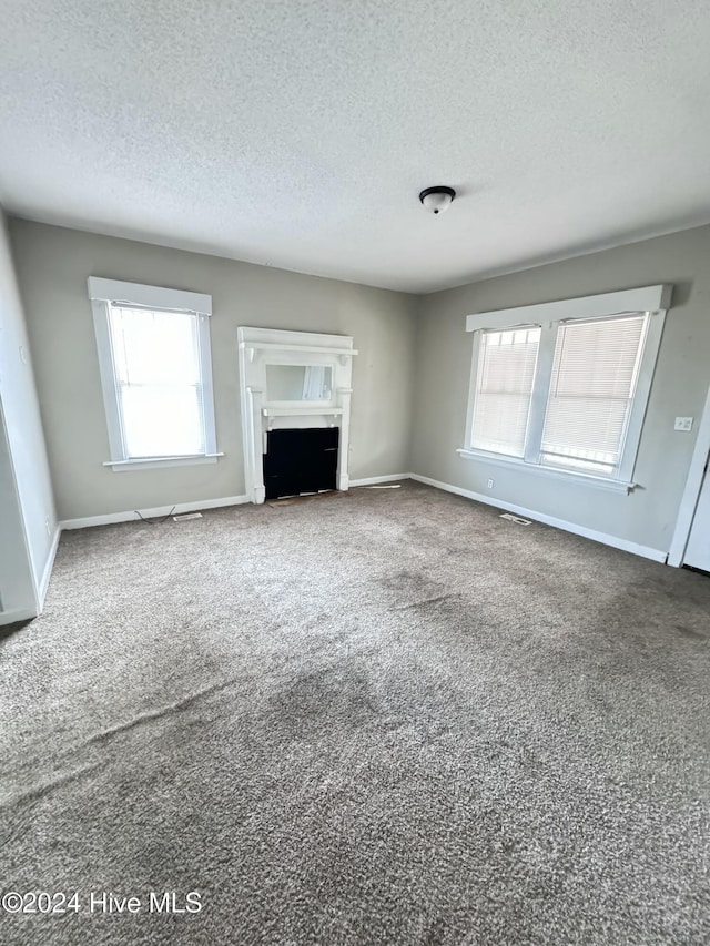 unfurnished living room featuring carpet flooring and a textured ceiling