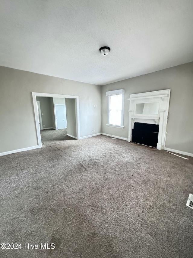 unfurnished living room with carpet and a textured ceiling