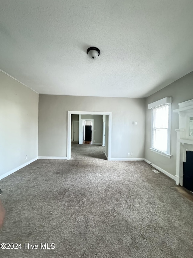 unfurnished living room with dark carpet and a textured ceiling