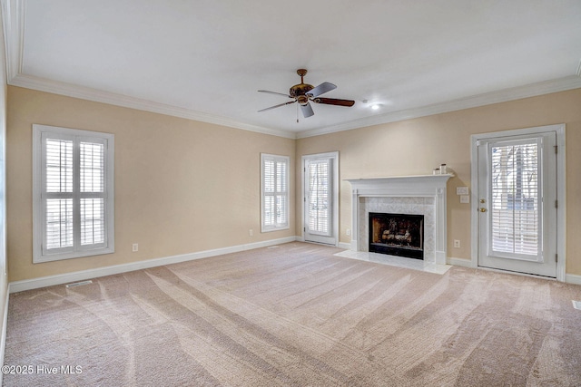 unfurnished living room featuring a fireplace, light colored carpet, ceiling fan, and ornamental molding