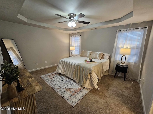 bedroom featuring a raised ceiling, ceiling fan, and dark carpet