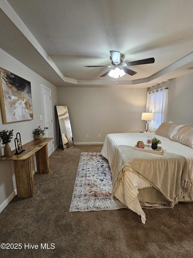 carpeted bedroom with ceiling fan and a tray ceiling