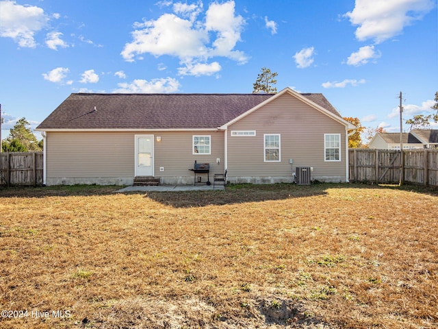 rear view of property featuring cooling unit, a patio area, and a yard