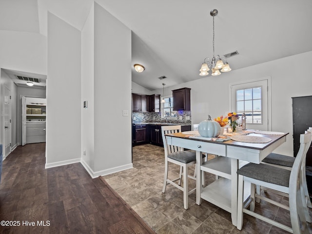 dining area featuring an inviting chandelier, vaulted ceiling, and sink