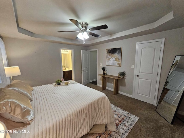 carpeted bedroom with ceiling fan, connected bathroom, and a tray ceiling