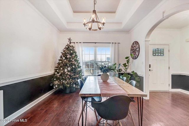 dining room with dark hardwood / wood-style flooring, a raised ceiling, and a notable chandelier