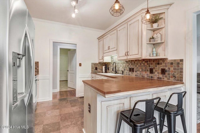 kitchen featuring hanging light fixtures, sink, stainless steel fridge, kitchen peninsula, and a breakfast bar area