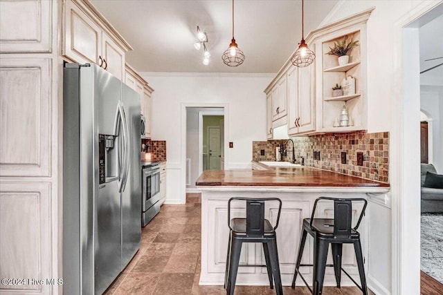 kitchen with sink, wood counters, a kitchen breakfast bar, decorative light fixtures, and appliances with stainless steel finishes