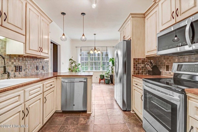 kitchen featuring sink, hanging light fixtures, appliances with stainless steel finishes, tasteful backsplash, and a chandelier