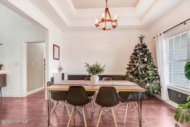 dining room featuring a raised ceiling, crown molding, a chandelier, and dark hardwood / wood-style floors