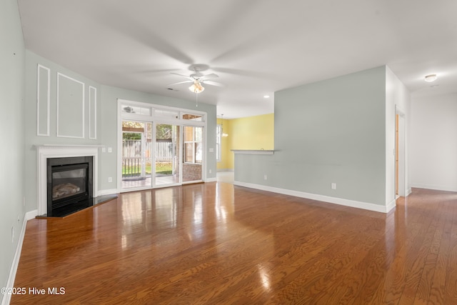 1107 Veranda Ct, Leland, NC 28451 - unfurnished living room featuring a glass covered fireplace, a ceiling fan, wood finished floors, and baseboards