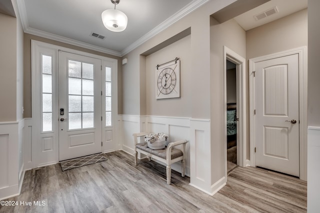 foyer entrance with light hardwood / wood-style floors and ornamental molding