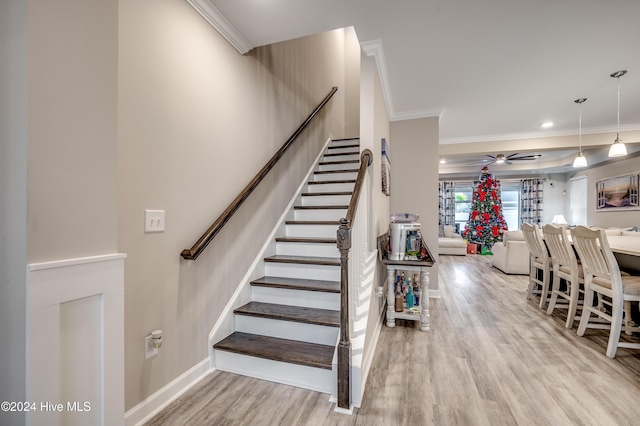 stairway with hardwood / wood-style flooring, ceiling fan, and ornamental molding