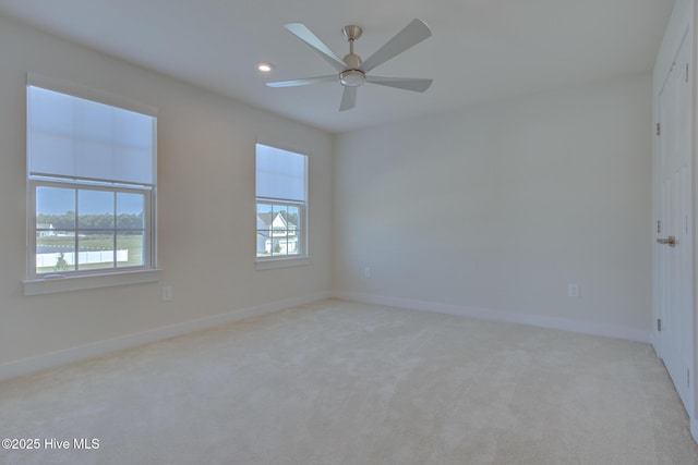 spare room featuring ceiling fan, light colored carpet, and a wealth of natural light