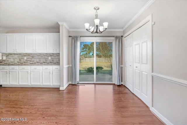 unfurnished dining area with hardwood / wood-style floors, an inviting chandelier, and crown molding