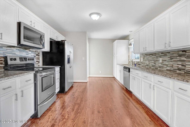 kitchen with white cabinets, decorative backsplash, stainless steel appliances, and light stone countertops