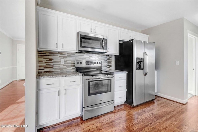 kitchen featuring light stone counters, white cabinetry, stainless steel appliances, and tasteful backsplash