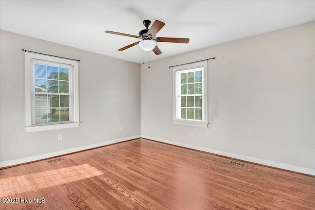 empty room featuring a wealth of natural light, hardwood / wood-style floors, and ceiling fan