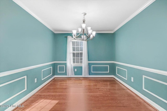 unfurnished dining area with wood-type flooring, an inviting chandelier, and ornamental molding