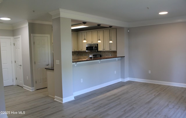 kitchen featuring kitchen peninsula, tasteful backsplash, crown molding, sink, and light hardwood / wood-style flooring