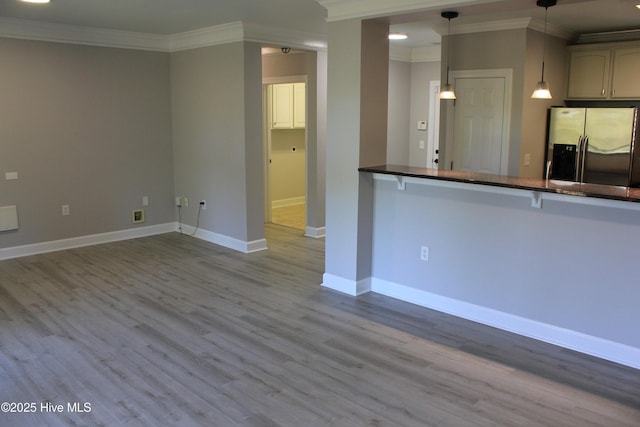 kitchen featuring stainless steel fridge with ice dispenser, light hardwood / wood-style flooring, kitchen peninsula, pendant lighting, and ornamental molding