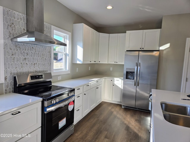 kitchen with appliances with stainless steel finishes, dark hardwood / wood-style flooring, wall chimney exhaust hood, sink, and white cabinets