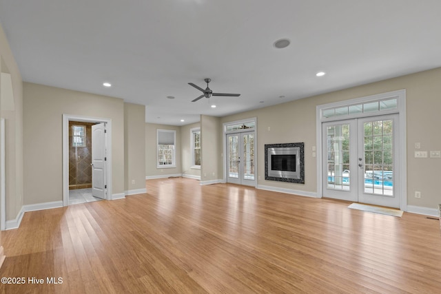 unfurnished living room featuring french doors, light wood-type flooring, and ceiling fan