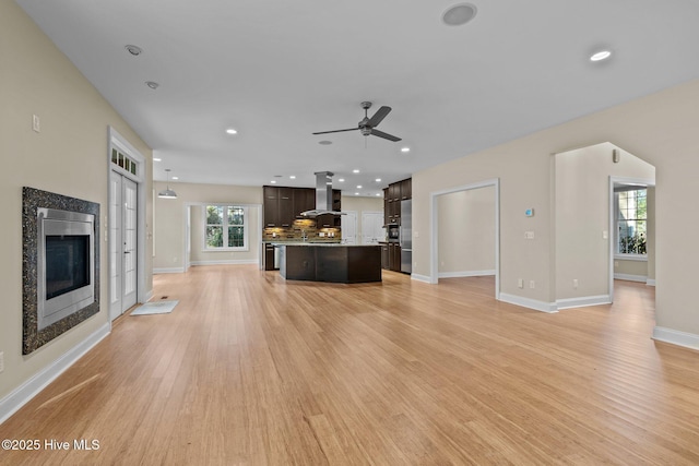 unfurnished living room featuring plenty of natural light, ceiling fan, light wood-type flooring, and a high end fireplace