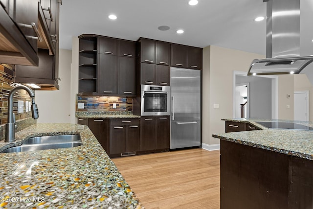 kitchen featuring sink, decorative backsplash, light wood-type flooring, island range hood, and stainless steel appliances