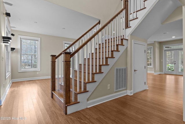 stairway with hardwood / wood-style floors and french doors